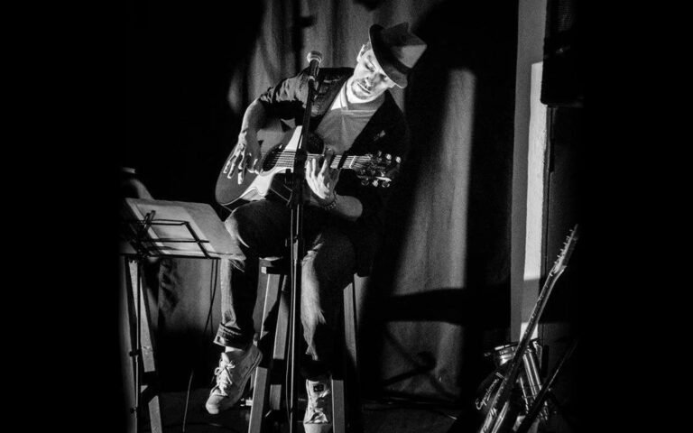 Martín Ponce tocando la guitarra en vivo sobre un escenario, foto en blanco y negro