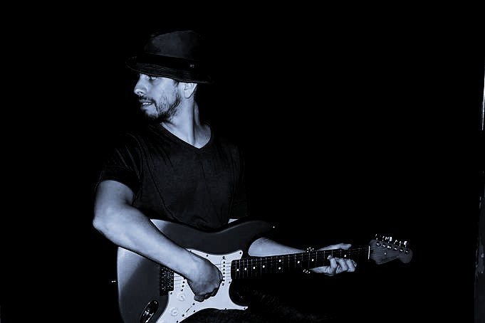 Martín Ponce con sombrero tocando la guitarra eléctrica